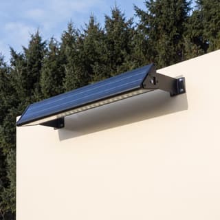 Illustration: a long solar LED downlight bar, switched off in daylight, above a blank roadside sign.