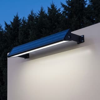 Illustration: a long solar LED downlight bar washing the face of a blank roadside sign at dusk.