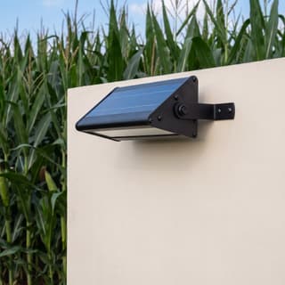 Illustration: a compact solar LED downlight, switched off in daylight, above a blank farm-entrance board.