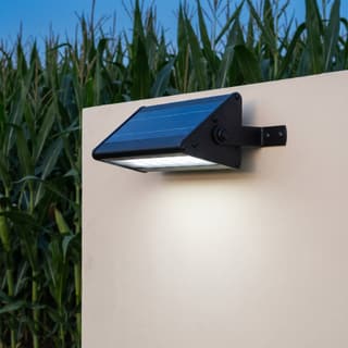 Illustration: a compact solar LED downlight washing a blank farm-entrance board at dusk.