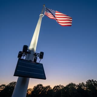 Illustration: a four-spot solar LED flag pole light uplighting an American flag at dusk.