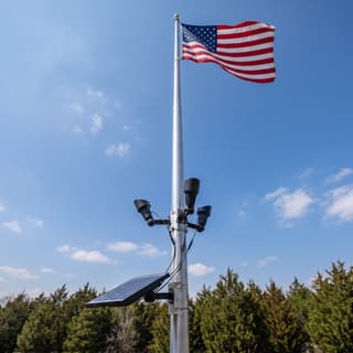 Illustration: a set of three solar LED spot lamps on a flagpole, switched off in daylight, below an American flag.