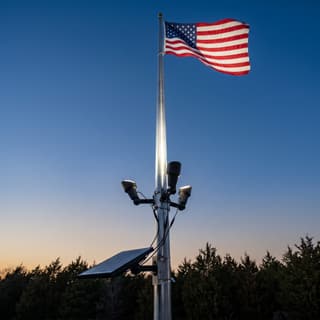 Illustration: a set of three solar LED spot lamps on a flagpole uplighting an American flag at dusk.