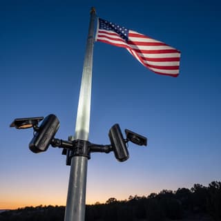 Illustration: a three-head solar LED flag pole light kit uplighting an American flag at dusk.