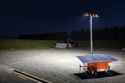 Illustration: a trailer-mounted solar light tower lighting a construction yard at night.