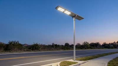 Illustration: an all-in-one solar LED street light switched on at dusk, seen from below.