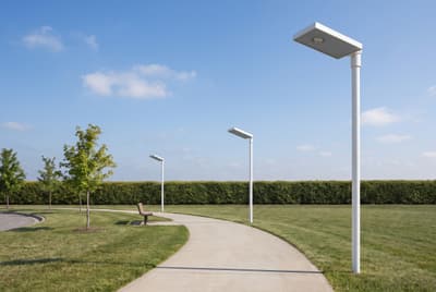 Illustration: solar LED walkway lights, switched off in daylight, along a park path.