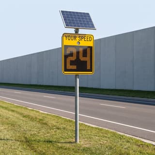 Illustration: a solar LED full-matrix radar speed sign beside a divided suburban parkway.