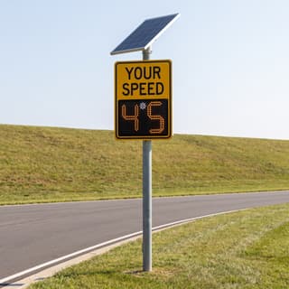 Illustration: a solar LED radar speed sign showing a driver's speed on a county park access road.