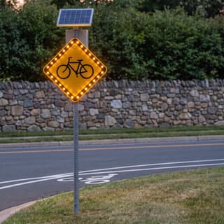 Illustration: a solar flashing bike lane sign glowing beside a bike lane on a suburban road after dark.