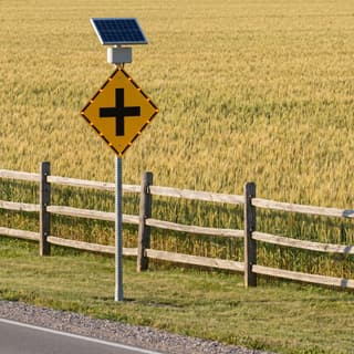 Illustration: a solar flashing intersection ahead sign on the approach to a rural crossroads.