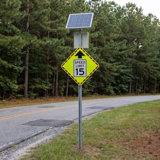 Illustration: a solar flashing reduced speed ahead sign with a speed limit plaque at a campground entrance road.