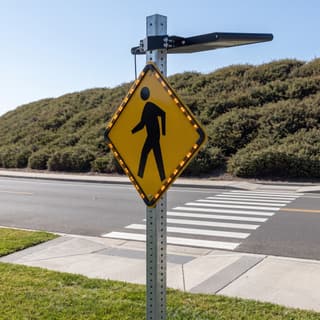 Illustration: a solar LED diamond retrofit frame lighting the border of a pedestrian crossing sign at a mid-block crosswalk.