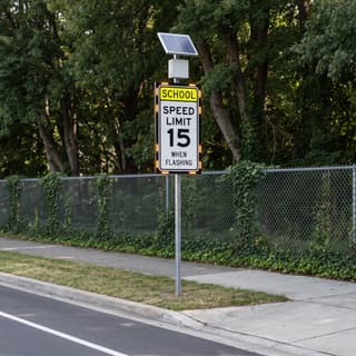 Illustration: a solar flashing school speed limit sign on a suburban arterial entering a school zone.