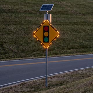 Illustration: a solar flashing signal ahead sign glowing on a two-lane arterial after dark.