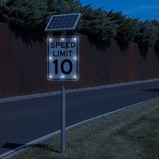 Illustration: a solar LED flashing 10 mph speed limit sign glowing on a private office-campus drive after dark.