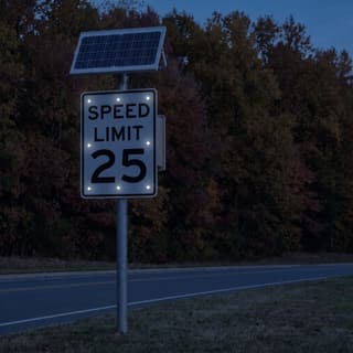 Illustration: a solar LED flashing 25 mph speed limit sign glowing on a suburban road beside an autumn wood after dark.