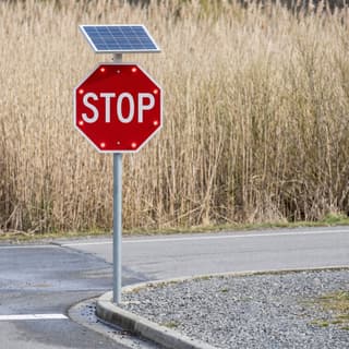 Illustration: a solar LED flashing stop sign at the top of a boat ramp lane in front of a lakeside reed bed.