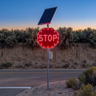 Illustration: a solar LED flashing stop sign glowing at a remote desert junction after dark.